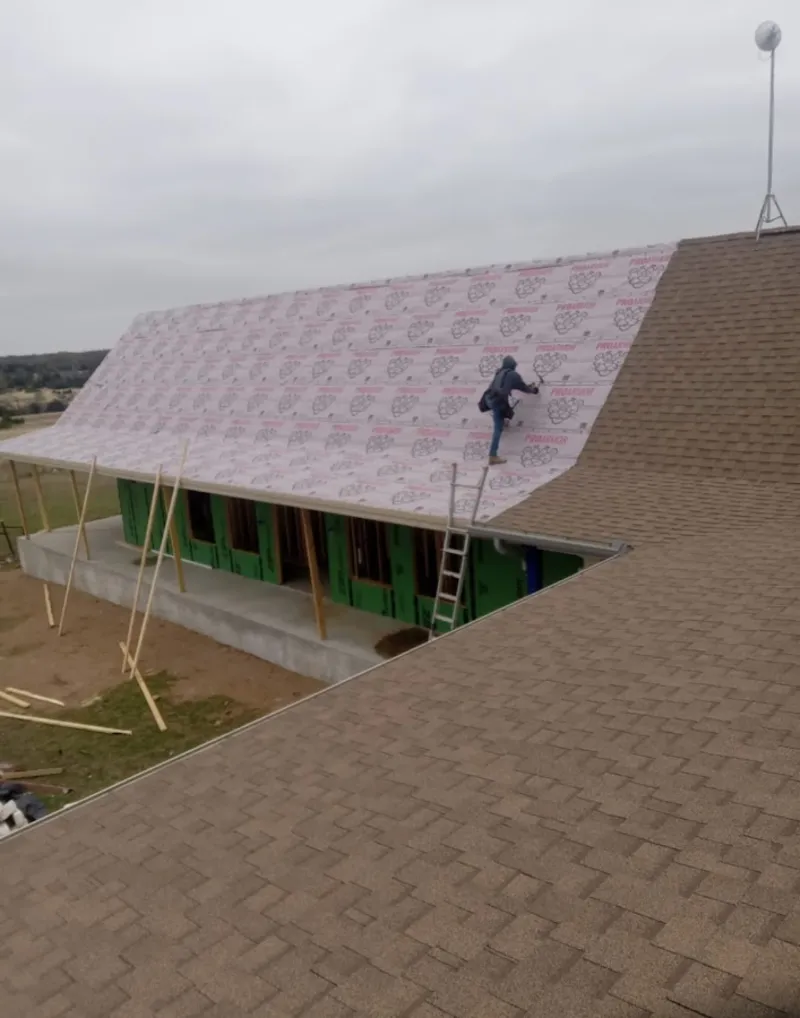Worker preparing underlayment for a metal roof installation in Laurinburg